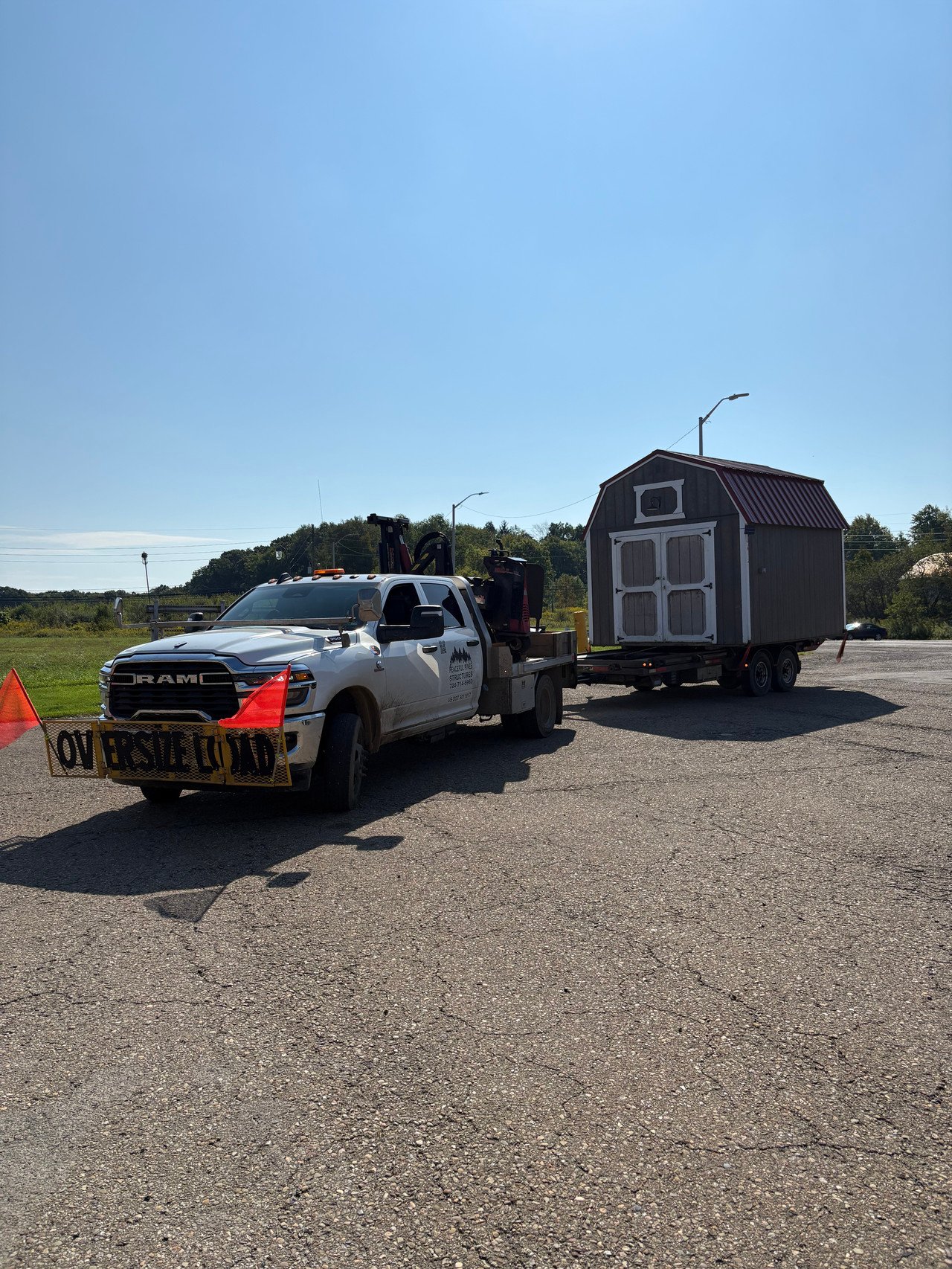 Peaceful Pines delivery truck carrying a gray lofted shed on its trailer